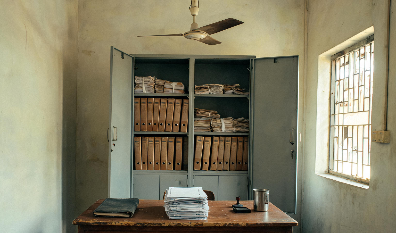 Accounts office in a Coimbatore factory with a steel cupboard of box files and bundled challans, the records a statutory compliance audit reviews