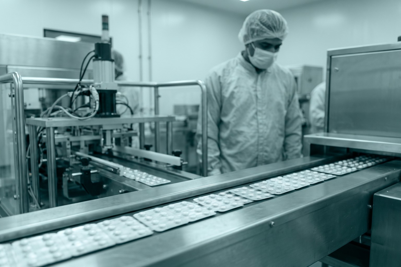Blister-packed tablets on a stainless-steel line in a pharmaceutical plant in India, representing LexComply's drug manufacturing license services